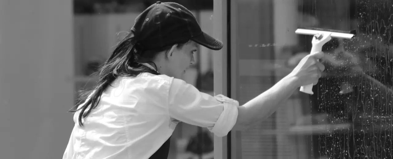 A woman cleaning a window. Jessica's Cleaning Service.